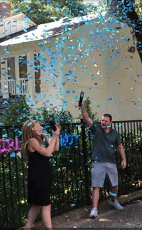Gender reveal cannon firing pink confetti at party